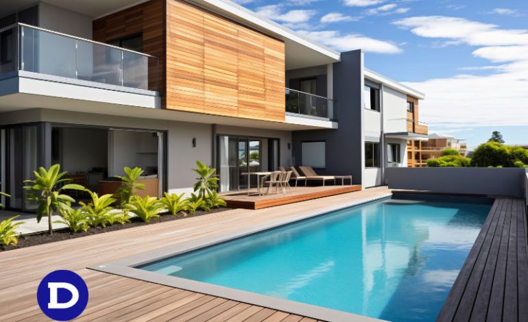 Projeto de piscina em casa, cercada com deck de madeira, cadeiras de sol e pequenos coqueiros de jardim